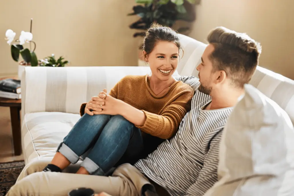 Happy couple sitting together on a couch and smiling warmly